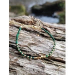 Bracelet malachite facettée 2 mm et cuivre plaqué or sur roche en Bretagne, perles vertes lumineuses avec mer floutée au fond
