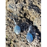 Boucles d’oreilles Labradorite création Magic Gaïa posées sur galets humides au bord de mer bretonne; intention: bouclier émotionnel, clarté, calme.