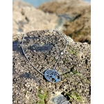Pendentif Arbre de Vie argenté sur chaîne fine au soleil, rocher côtier couvert de balanes en Bretagne, équilibre et protection symbolique