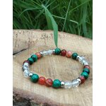 Bracelet prémenstruel 6 mm (malachite, cornaline, cristal de roche) posé sur pierre beige en extérieur, feuillage vert en arrière-plan, création Magic Gaïa; intention apaisement, équilibre émotionnel.