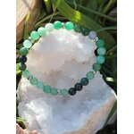 Bracelet Psoriasis 6 mm posé sur géode de quartz blanc dans l’herbe, amazonite, agate mousse et aventurine verte pour relâchement émotionnel et stabilité du ressenti