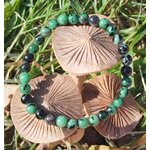 Bracelet rubis zoïsite en perles rondes sur champignons décoratifs dans l’herbe, créativité vivante, assurance personnelle et harmonie émotionnelle