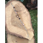 Bracelet rune de protection en bois création Magic Gaïa, chaîne argentée avec perles quartz rose et grenat, posé sur tranche de bois et herbe, intention: protection douce et apaisement