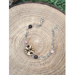 Bracelet rune de protection en bois Magic Gaïa, chaîne argentée avec perles quartz rose et grenat, posé sur rondin de bois, intention: apaisement et protection.