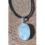 Pendentif ovale en labradorite blanche sertie argent 925 sur cordon noir, posé sur pierre beige au soleil, bijou en pierre naturelle lié à la clarté d’esprit, à la tranquillité et à la finesse intuitive.