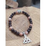 Bracelet viking en pierre de soleil et grenat posé sur bois clair, triquetra argentée et rune centrale, détermination, stabilité et esprit guerrier