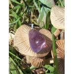 Pendentif en amétrine aux reflets violets suspendu parmi des champignons et feuillages, dans un décor naturel, pierre naturelle évoquant le calme du mental, le recul et l’harmonie intérieure.