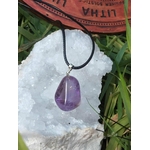 Pendentif en amétrine violette sur cordon noir, présenté sur un amas de quartz  et décor végétal, pierre naturelle associée à la paix intérieure, à la finesse d’esprit et à l’équilibre émotionnel.