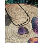 Pendentif en amétrine violette sur cordon noir, posé sur bois avec décor minéral en fond, pierre naturelle reliée au discernement, au recentrage et à la sérénité émotionnelle.