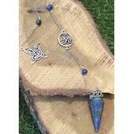 Pendule en lapis-lazuli bleu avec chaîne personnalisée argentée et symboles celtiques, présenté sur une tranche de bois dans un décor naturel inspirant recentrage et intuition.