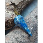 Pendule en lapis-lazuli bleu profond posé entre bois flotté et pierre brute, dans un décor naturel inspirant intuition, clarté mentale et apaisement.