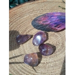 Pierres roulées d’amétrine aux reflets violets sur rondin de bois avec plume colorée, pierres naturelles évoquant la finesse d’esprit, la douceur intérieure et le recentrage.