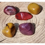 Pierres roulées de jaspe mookaïte aux teintes jaunes, rouges et bordeaux sur support en bois sculpté, pierres naturelles associées à l’élan vital, à la solidité émotionnelle et à l’assurance