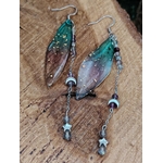 Boucles d’oreilles fée création Magic Gaïa posées sur bois brut, avec ailes translucides bleu-vert, pampilles argentées, lunes et étoiles, dans une ambiance féerique, douce et pleine de poésie.