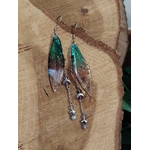 Boucles d’oreilles fée création Magic Gaïa posées sur bois naturel, avec ailes translucides bleu-vert, pampilles lunes et étoiles, dans une ambiance féerique et apaisante propice à la douceur.