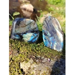 Deux labradorites forme libre aux reflets bleus posées sur mousse et rocher en Bretagne, près d’un ruisseau, pierres naturelles associées à la protection douce, au calme intérieur et à la profondeur intuitive.