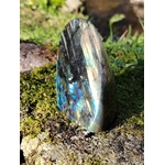 Labradorite forme libre aux reflets bleus posée sur mousse et rocher en Bretagne, près d’un ruisseau, pierre naturelle associée à la douceur émotionnelle, à la clarté et à l’intuition posée.