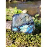 Labradorite forme libre irisée bleue posée sur mousse bretonne au bord d’un ruisseau, pierre naturelle reliée au calme, à la présence à soi et à la finesse de perception.