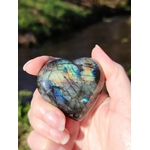 Main tenant un cœur en labradorite poli aux reflets bleus, en extérieur, pour soutenir la protection énergétique, calmer le mental et réveiller l’intuition.