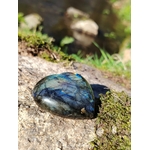 Coeur labradorite poli aux reflets bleus posé sur granit breton avec mousse et ruisseau en arrière-plan, pour protéger l’aura, apaiser et soutenir l’intuition.