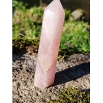 Pointe de quartz rose facettée dressée sur granit en Bretagne, herbes et mousse autour, lumière naturelle, pour apaiser, réconforter et ouvrir le cœur avec douceur.