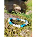 Bracelet TDAH création Magic Gaïa posé sur tapis de mousse en Bretagne avec rocher flou, apatite et sélénite pour apaiser la dispersion et soutenir l’attention