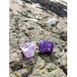 Deux améthystes brutes violettes posées sur un rocher strié en Bretagne, textures minérales et lumière naturelle, pour calmer le mental, apaiser et clarifier.