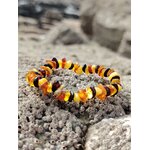 Bracelet ambre enfant baroque sur rocher granitique en Bretagne, éclats miel et cognac, sérénité, cocon rassurant et douceur affective