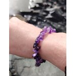 Bracelet améthyste baroque porté au poignet sur rochers en bord de mer, nuances violettes, clarté mentale et énergie apaisante