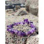 Bracelet améthyste violette sur rocher de granit avec galets et mer floutée, pierre naturelle associée au recentrage et à l’intuition