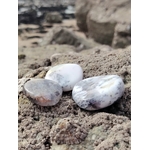 Galets de calcédoine dendritique posés sur les rochers en Bretagne avec la mer en arrière-plan, pierres naturelles associées à la fluidité intérieure, au recul et à la sérénité.