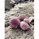 Pierres roulées en quartz fraise naturel posées sur une roche en Bretagne, pierres naturelles associées au réconfort, à la sensibilité apaisée et à l’harmonie intérieure.
