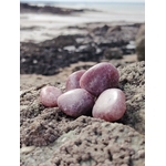 Pierres roulées en quartz fraise posées sur une roche en bord de mer en Bretagne, pierres naturelles associées à la douceur, à la joie intérieure et à l’équilibre affectif.