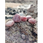 Pierres roulées en quartz fraise naturel posées sur une roche au bord de la mer en Bretagne, pierres naturelles liées à la vitalité douce, à l’élan affectif et à la chaleur intérieure.