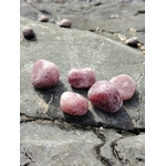 Pierres roulées en quartz fraise naturel posées sur une roche au bord de l’eau en Bretagne, pierres naturelles évoquant la fluidité émotionnelle, la douceur intérieure et la paix du cœur.