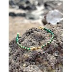 Bracelet malachite facettée 2 mm et cuivre plaqué or sur rocher en Bretagne, plage et coquillage en arrière-plan, bijou vert lumineux