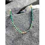 Bracelet fin en malachite facettée photographié sur roche sombre en Bretagne, contraste minéral et éclat discret du cuivre plaqué or