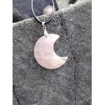 Pendentif lune en quartz rose naturel posé sur roche sombre en Bretagne, bijou en pierre naturelle associé à la tendresse, au réconfort et à la paix du cœur.