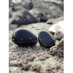 Pierre roulée d’obsidienne noire sur roche bretonne dans un décor minéral naturel, pierre naturelle associée à l’enracinement, au calme du mental et à l’équilibre intérieur.