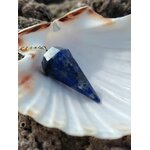 Pendule en lapis-lazuli bleu profond présenté sur un coquillage blanc dans un décor minéral naturel, une mise en scène apaisante évoquant intuition, recentrage et clarté intérieure.
