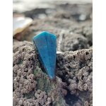 Pendule en apatite bleue posé sur un rocher breton couvert de balanes, dans un décor marin doux et minéral, photo prise en Bretagne, évoquant intuition, apaisement émotionnel et clarté intérieure.