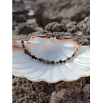 Bracelet doré en labradorite dans un coquillage blanc sur rochers bretons, reflets bleutés, apaisement et inspiration