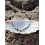 Bracelet labradorite en acier inoxydable doré posé dans un coquillage blanc sur rochers en bord de mer, protection douce et intuition.