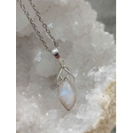 Pendentif elfique en péristérite argent 925 avec chaîne en acier inoxydable, suspendu devant un amas cristallin aux nuances douces, reflet bleuté délicat, décor minéral évoquant intuition, apaisement et sérénité.