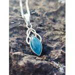 Pendentif elfique en apatite bleue monté en argent 925, photographié sur des rochers bretons sombres, collier en pierre naturelle associé à la créativité, à la confiance douce et à la paix émotionnelle.
