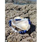Bracelet migraine 6 mm en lapis-lazuli, labradorite et sélénite dans un coquillage sur rochers bretons face à la mer, apaisement du mental et clarté intérieure