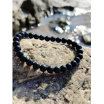 Bracelet tourmaline noire 6 mm sur roche claire veinée en décor minéral breton, bouclier énergétique, ancrage profond et force tranquille