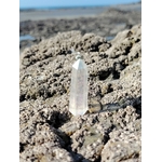 Pointe Angel Aura posée sur les rochers en Bretagne face à l’horizon, cristal irisé évoquant l’ouverture, la douceur émotionnelle et la tranquillité du mental.