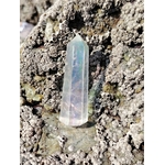 Pointe Angel Aura dressée entre les rochers en Bretagne, cristal lumineux aux reflets changeants associé au recentrage, à la fraîcheur mentale et à l’harmonie intérieure.