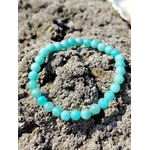 Bracelet en amazonite naturelle 6 mm sur roche granitique en bord de mer, nuances bleu-vert, pierre de réconfort et d’apaisement du mental